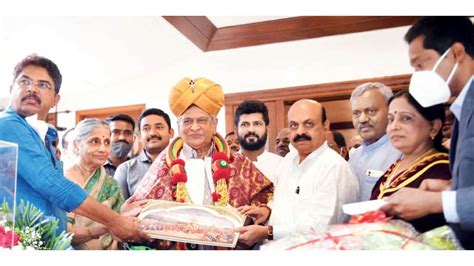 S.M. Krishna, former Chief Minister of Karnataka, being felicitated at a public event surrounded by dignitaries, wearing a traditional turban and garlands, symbolizing recognition of his contributions to Karnataka's development.